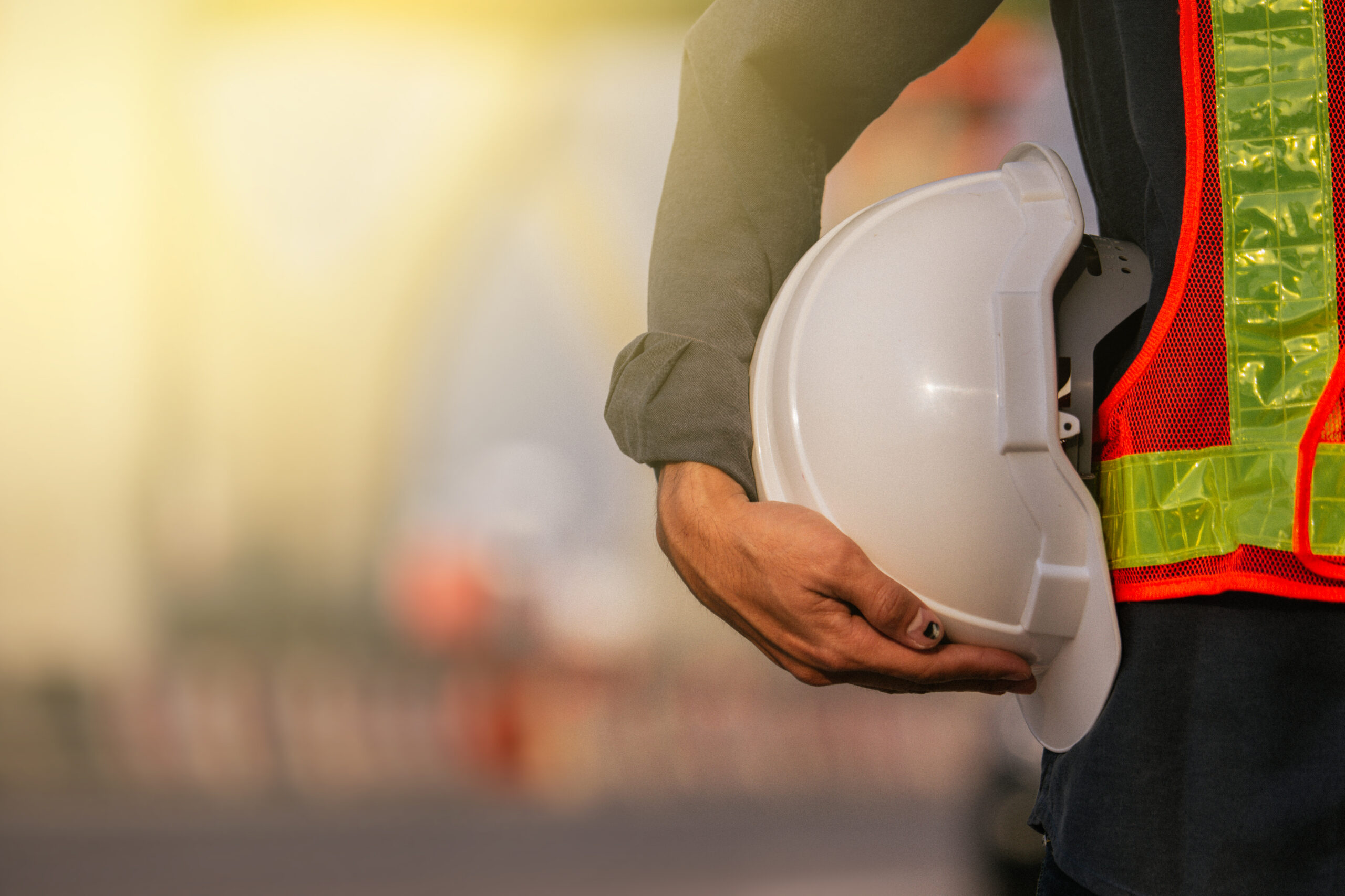 Close up engineer hold hard hat site construction background
